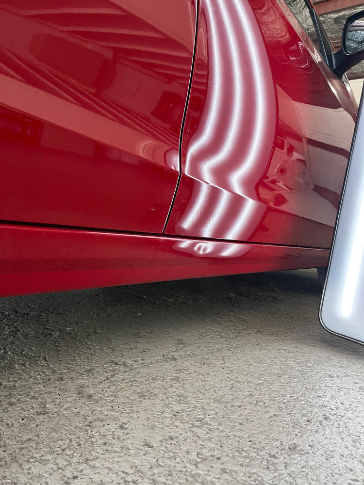 red car that has had a dent removed from the panel